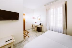 塞维利亚Basic Hotel Doña Manuela的白色卧室配有床和书桌