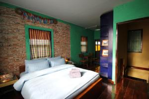宋卡班奈娜旅馆的卧室配有一张白色大床和砖墙