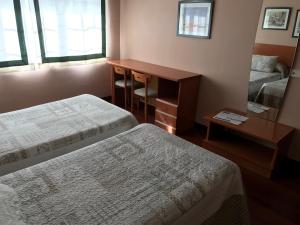 费罗尔Hostal La Frontera的客房设有两张床、一张桌子和一面镜子。