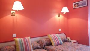 拉福雷富埃南Maison Hôtel Aux Cerisiers的一间卧室设有红色的墙壁、一张沙发和两盏灯。