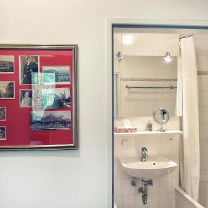 旧天鹅堡豪夫维斯酒店的一间带水槽的浴室和墙上的照片