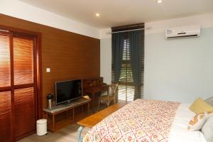 科罗尔贝壳度假公寓式酒店的一间卧室配有一张床和一张书桌及电视