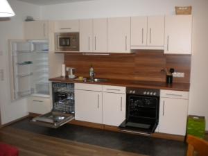 瓦格赖恩Appartement Andi的厨房配有白色橱柜、水槽和冰箱。