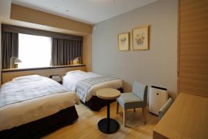 福冈福冈蒙特埃马纳酒店的酒店客房,配有两张床、一张桌子和一把椅子