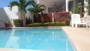 恰卡拉卡萨查卡拉酒店的一座房子旁的游泳池,配有两把白色椅子