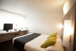 保拉扎克Ampaline HOTEL - Perigueux Boulazac的一间卧室配有一张带黄色枕头的床和一张书桌