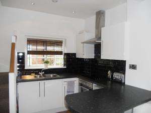 亚姆Yarm View Cottages的厨房配有白色橱柜和黑色台面