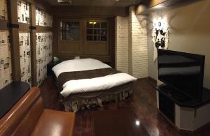 名古屋派亚特酒店（仅限成人）的一间设有床铺和电视的房间