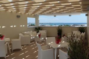 托雷拉皮罗Hotel Perla Dello Ionio的一间设有白色桌子和白色椅子的餐厅,享有海景