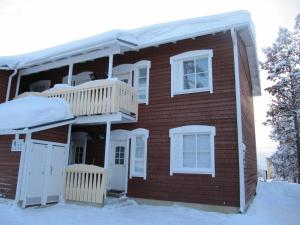 萨利色尔卡Lapin Kutsu Holiday Homes的红砖房子,在雪中设有阳台