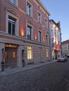 施特拉尔松德老瑞典使馆公寓式酒店的街道上的建筑物,前面有停车位