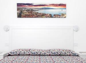 阿纳卡普里珀莱欧别墅旅馆的白色卧室配有一张床,墙上挂着一幅画
