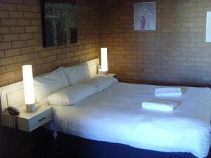 墨尔本埃森顿汽车旅馆的卧室配有白色的床,上面有两本书