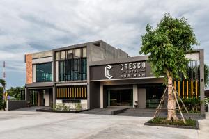 武里南Cresco Hotel Buriram的前面有棵树的建筑