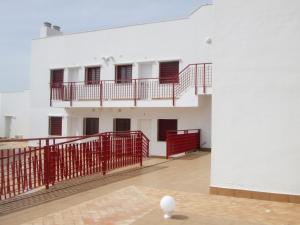 科尼尔-德拉弗龙特拉hotel apartamentos turisticos san vicente的一间空房间,有一座白色的建筑,有红色的栅栏