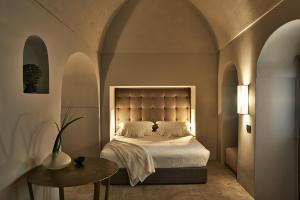潘泰莱里亚Sikelia Luxury Hotel的一间卧室配有一张床、一张桌子和拱门