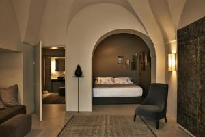 潘泰莱里亚Sikelia Luxury Hotel的一间卧室配有一张床、一张沙发和一把椅子