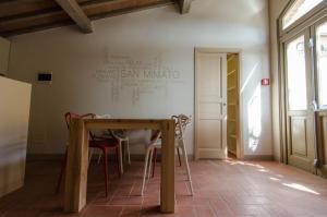 圣米尼亚托Ostello San Miniato的墙上有标牌的房间的桌椅