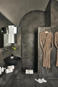 潘泰莱里亚Sikelia Luxury Hotel的浴室配有水槽和墙上的浴袍