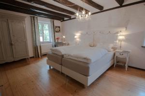 埃尔克拉特佳斯特豪斯瓦恩穆勒酒店的卧室配有一张白色大床和吊灯。