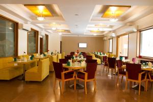 浦那7 Apple Hotel Pimpri Pune的一间在房间内配有桌椅的餐厅