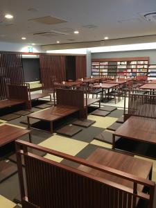 所泽市Spa胶囊旅馆（仅限男性）的空的图书馆,有木桌和书籍