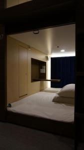 所泽市Spa胶囊旅馆（仅限男性）的卧室设有一张白色大床和一扇窗户。