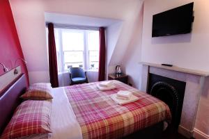 爱丁堡Regent House Hotel - City Centre Hotel的一间卧室配有一张带壁炉和电视的床。
