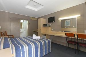 SarinaTandara Hotel Motel的酒店客房,配有一张床和两把椅子