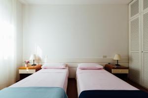 蓬塔阿拉Residence Renaione的配有两张桌子和两盏灯的房间的两张床