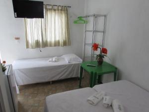 乌巴雅拉Pousada Sitio Costa Verde的客房设有两张床、一台电视和一张桌子。