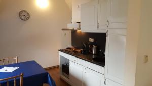 兰德赫拉夫瓦坎提林堡兰德格拉芙公寓的厨房配有白色橱柜、桌子和时钟
