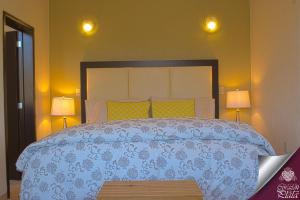 瓜纳华托科拉松普拉塔套房公寓式酒店的一间卧室配有一张带蓝色被子的床和两盏灯。