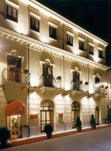 阿尔卡莫Hotel Centrale Spa & Relax的一座白色的大建筑,晚上设有窗户和阳台