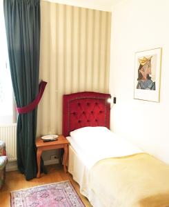 隆德康科迪亚酒店的一间卧室配有一张带红色床头板的床和一张桌子