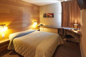 里摩日Cit'Hotel Les Alizés的酒店客房配有一张床、一张书桌和一张书桌。