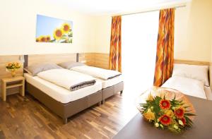 OttenschlagPension Einsiedl的一间卧室配有两张床和一张鲜花桌