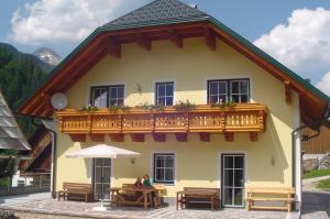茵特斯托德菲尔霍夫林纳盖特农家乐的黄色的房屋设有木制阳台和桌子