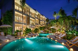 坎古苍谷海滩公寓的酒店设有带椅子和遮阳伞的游泳池