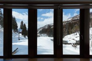 野沢野泽豪斯酒店的透过窗户可欣赏到白雪 ⁇ 的山景