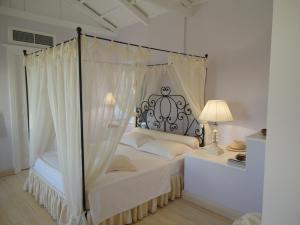 伊兹拉House Aquata的卧室配有带白色床单的天蓬床