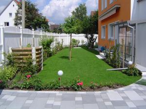 纽伦堡古曼度假公寓的花园设有白色的围栏和绿色的草地