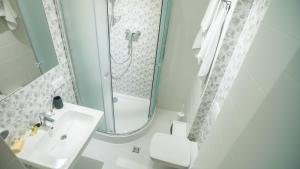 利沃夫Central Hotel的带淋浴和盥洗盆的白色浴室
