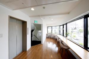 名古屋Guesthouse TOHO的长长的走廊,配有椅子和长桌