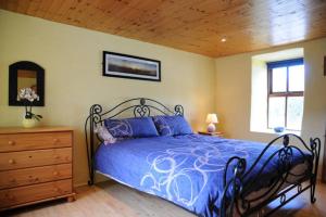 丁格尔Griffins Holiday Cottage的一间卧室设有蓝色的床和木制天花板