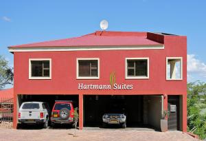 温特和克Hartmann Suites Serviced Self-Catering Apartments的一座红色的建筑,有两辆车停在车库里