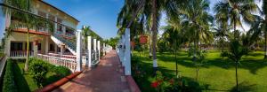 坦贾武尔GReaT Trails Riverview Thanjavur By GRT Hotels的一座棕榈树环绕的绿色庭院建筑