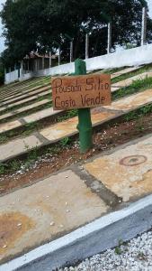 乌巴雅拉Pousada Sitio Costa Verde的坐在长凳上的一个木标志