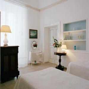 马丁纳弗兰卡卡赛斯帕梭尼历史中心乡村酒店的白色卧室设有两张床和一张鲜花桌