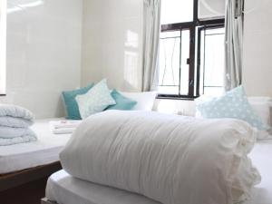 香港New Yan Yan Guest House reception 9th floor Flat E4 E6的一张带白色被子和枕头的床